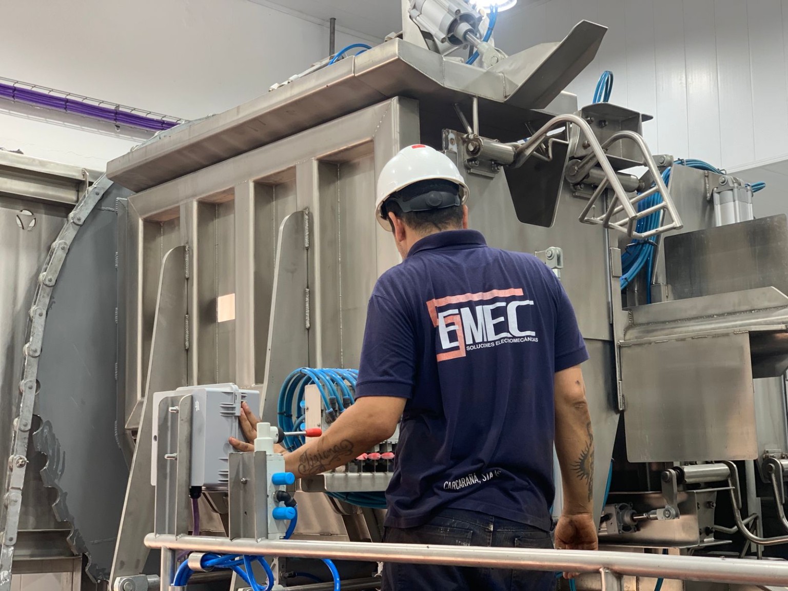 Técnico de Semec junto a un equipo industrial con mandos eléctricos y neumáticos